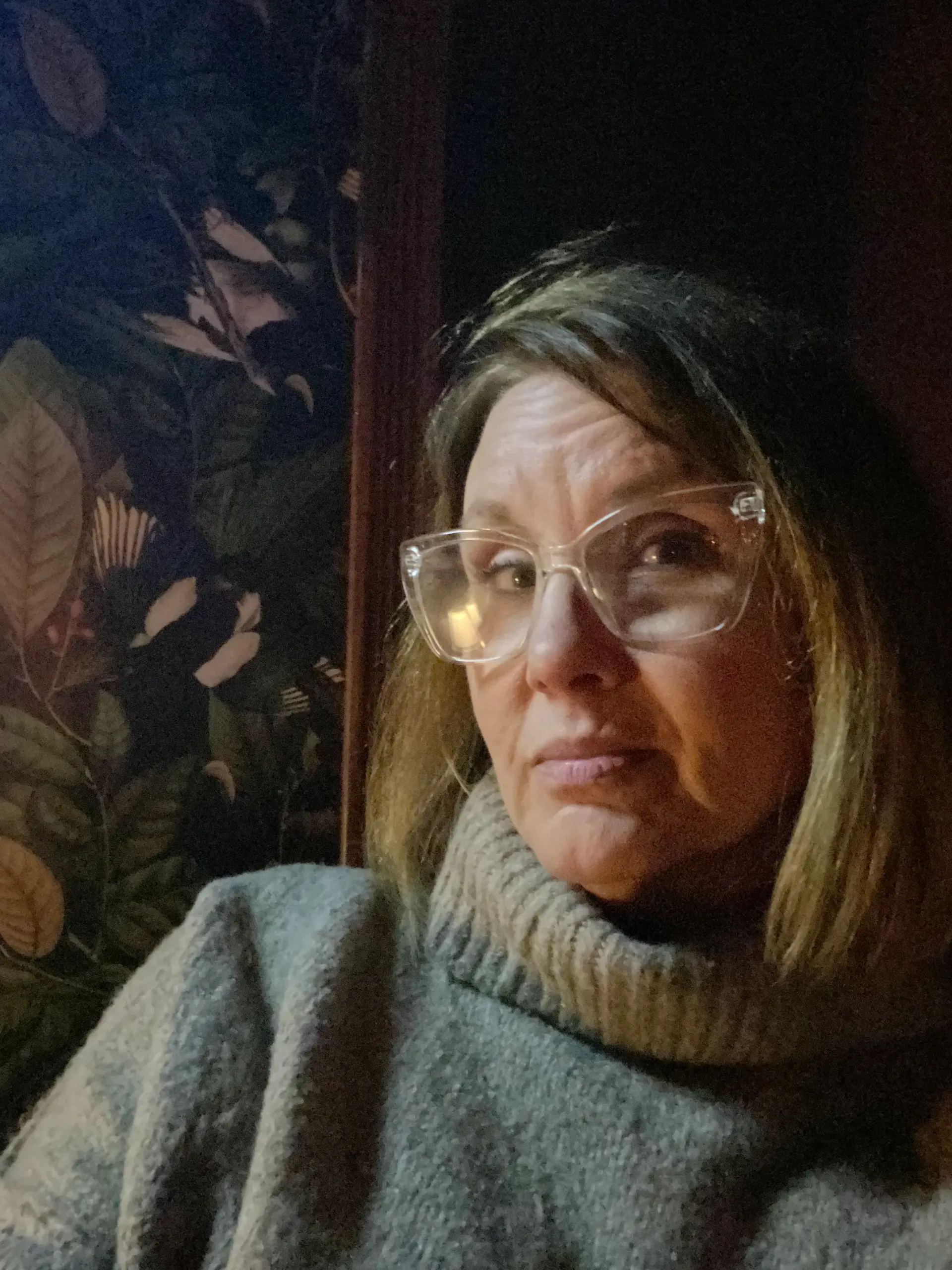 Deb Cotton in candlelight against dark botanical wallpaper